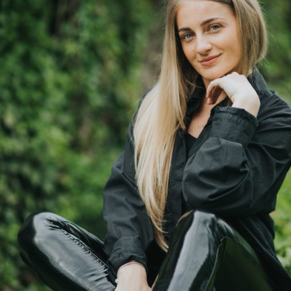 vertical-shot-fashionable-caucasian-blonde-female-posing-surrounded-by-greenery